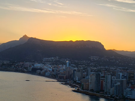 sunset city skyline, golden sunset over urban coastline, calm evening with mountain and ocean viewsの写真素材
