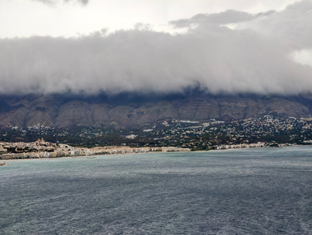 intense storm brewing over seaside town, chaotic weather patterns surging above bustling coastalの写真素材