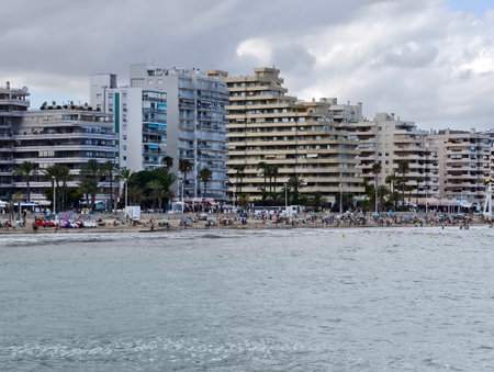 lively seaside scene with numerous umbrellas and busy coastal promenade filled with visitorsの写真素材
