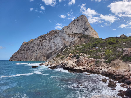imposing limestone cliffs dominate panoramic coastal landscape with wild surf and azure skyの写真素材