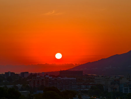 A breathtaking sunset stunningly illuminating the city skyline and majestic mountains in warm, inviting huesの写真素材