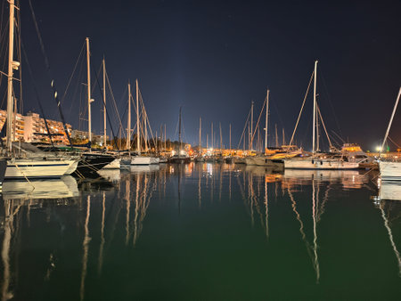 calm boats with glowing lights, symmetrical sailboats mirrored in still waters with lit apartments