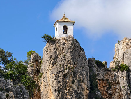 white tower over rugged landscape, cliffside bell tower rises above rugged terrain and vast skyの写真素材