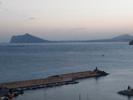 calm dawn at harbor shore, early morning peaceful pier view with distant vessels and pastel skyの写真素材