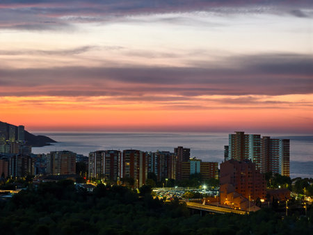 vibrant sunset over seaside urban area, calm waterfront view with illuminated city and sky featuresの写真素材