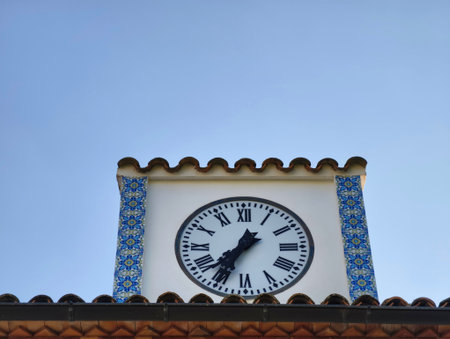 Charming town clock tower with vivid ceramic details and serene midday sunlight highlighting...