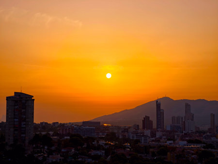 Twilight cityscape scene, Dusk horizon featuring distant mountain range, Serene silhouette of city towers against sunsetの写真素材