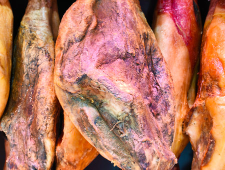 vivid pink ham slices with inviting aroma, chef slicing vibrant jamon on wooden board under warmの写真素材