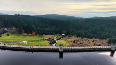 Infrastructure inspection aerial, Surveyor assessing dam infrastructure amidst lush hills and agricultural fieldsの写真素材
