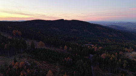 Gentle dawn on mountain ridge, Peaceful dawn illuminating distant valley with silhouette hills and dark woodedの写真素材