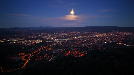 Bright metropolis alive after dusk with motion, Cityscape illuminated by warm lamps and shimmering water surfacesの写真素材
