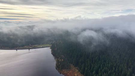 soft morning mist overlays calm lake surface with quiet clouds overhead in peaceful harmonyの写真素材