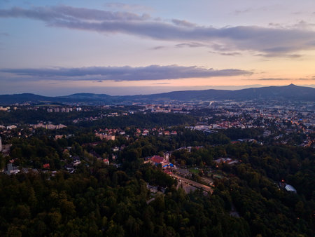 Sunset Over Rolling Hills With Town Lights Appearing, Colorful Sky Gradient And Soft Cloud Layers, Warm Tonesの写真素材
