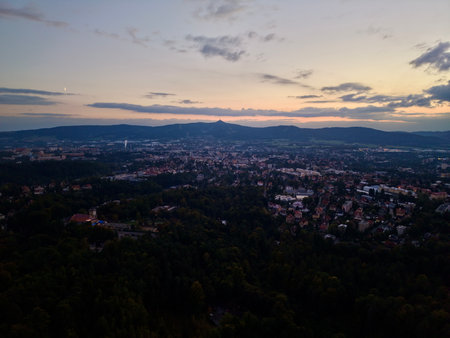 Sunset Town Panorama From Hilltop Showing Suburban Rooftops And Distant Mountain Silhouette, Warm Golden Glowの写真素材