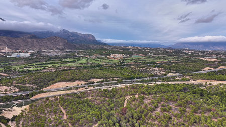 aerial view rugged mountain valley and winding river under heavy cloud with rocky ridgelinesの写真素材