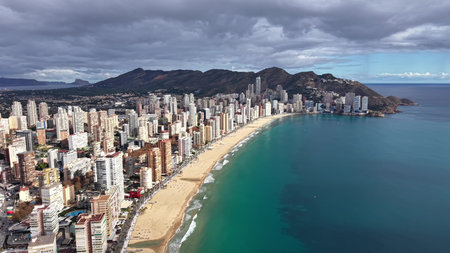 aerial crescent beach and urban strip captured by drone, sweeping reveal of continuous highrises, golden sandの写真素材
