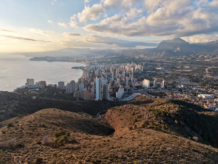 Aerial coastal city skyline at sunset, highrise resort buildings hugging shoreline, golden light reflectingの写真素材