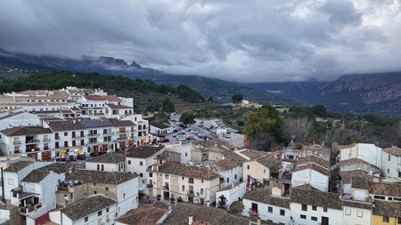 Windy mountain village panorama with storm clouds rolling over peaks, terracotta rooftops and narrow streets,の写真素材