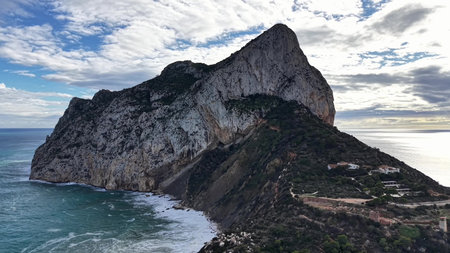 towering coastal rock under brooding clouds, editorial shoot captures raw surf, windblown spray, texturedの写真素材