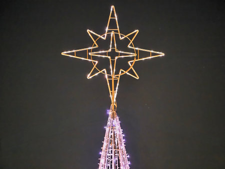 Star tree topper glowing against sky, slender conical tree wrapped with lights, soft halo and subtle...