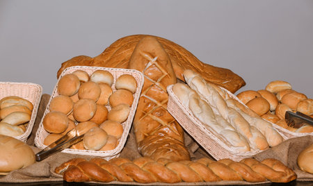  Assorted freshly baked bread and buns displayed on table against the light grey 