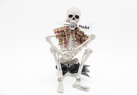 skeleton sitting and holding message tag in his jaws on white background