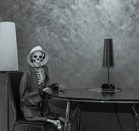 Happy skeleton sitting behind the table in dark dramatic room environment, wearing leather jacket,...