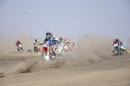 Russia, Samara - April 17,2010, Regional Championship motocross, a group of riders the first corner after the start, the dusty trailのeditorial素材