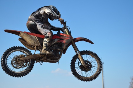 Motocross rider A. Stepanov performs jump, located high in air against blue skyの写真素材