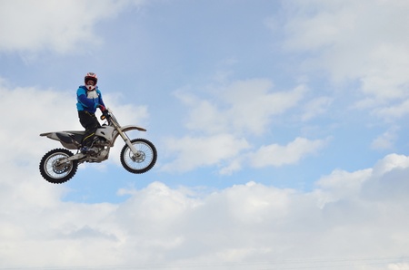 motocross practice rider high flight in the rack against the blue sky and cloudsの写真素材