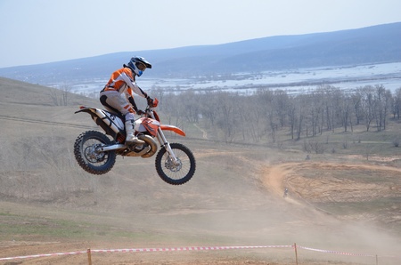 Motocross rider on the motorbike takes off on a high hill ground turned his head facing the cameraの写真素材