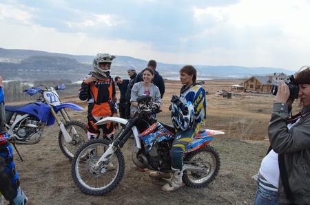 RUSSIA, SAMARA - April 29: Motocross racers group rests on a background of mountains and stormy sky, the girl making sportsmenâs photographs the Regional Motocross practice April 29, 2011 in Samara, Russiaのeditorial素材