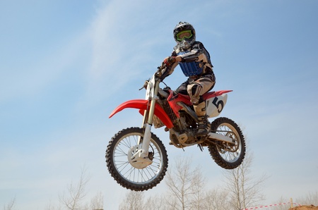 Motocross motorbike racer performs a jump efficient, hangs in the open airの写真素材
