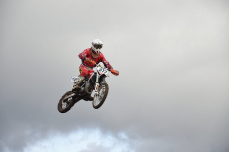 RUSSIA, SAMARA, CHAPAYEVSK - OCTOBER 17: The spectacular jump moto racer I. Baranov on the background a stormy sky the Open Cup "Volga" motocross on October 17, 2011 in Chapayevsk, Samara, Russiaのeditorial素材