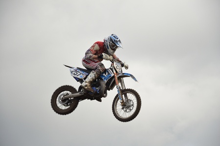 RUSSIA, SAMARA, CHAPAYEVSK - OCTOBER 17: High flight of motorcycle racer A. Guryev on a motorcycle on the background of clouds the Open Cup "Volga" motocross on October 17, 2011 in Chapayevsk, Samara, Russiaのeditorial素材