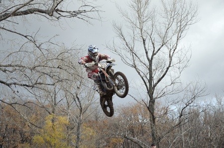 RUSSIA, SAMARA, CHAPAYEVSK - OCTOBER 17: A jump rider A. Guryev on the background an autumn forest the Open Cup "Volga" motocross on October 17, 2011 in Chapayevsk, Samara, Russiaのeditorial素材