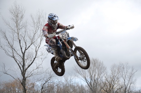 RUSSIA, SAMARA, CHAPAYEVSK - OCTOBER 17: High flight of motorcycle racer A. Guryev on the background of clouds the Open Cup "Volga" motocross on October 17, 2011 in Chapayevsk, Samara, Russiaのeditorial素材