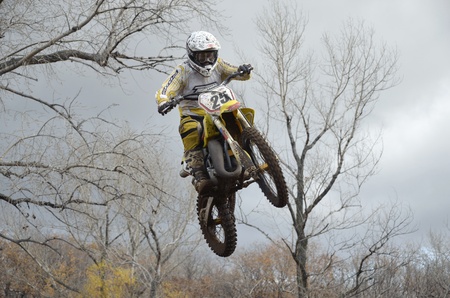 RUSSIA, SAMARA, CHAPAYEVSK - OCTOBER 17: A jump rider unknown on the background an autumn forest the Open Cup "Volga" motocross on October 17, 2011 in Chapayevsk, Samara, Russiaのeditorial素材