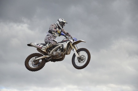 RUSSIA, SAMARA, CHAPAYEVSK - OCTOBER 17: The spectacular jump motocross racer A. Ivanyutin on the background a stormy sky the Open Cup "Volga" motocross on October 17, 2011 in Chapayevsk, Samara, Russiaのeditorial素材
