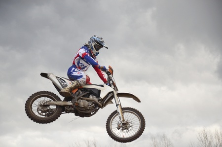 RUSSIA, SAMARA, CHAPAYEVSK - OCTOBER 17: A leap over the hill, motorcycle racer A. Nikishkin on the background a stormy sky the Open Cup "Volga" motocross on October 17, 2011 in Chapayevsk, Samara, Russiaのeditorial素材