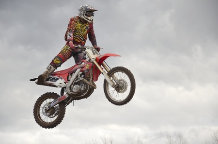 RUSSIA, SAMARA, CHAPAYEVSK - OCTOBER 17: The spectacular jump motocross racer unknown on the background a stormy sky the Open Cup "Volga" motocross on October 17, 2011 in Chapayevsk, Samara, Russiaのeditorial素材