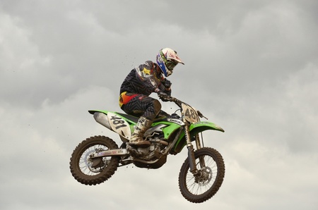 RUSSIA, SAMARA, CHAPAYEVSK - OCTOBER 17: The spectacular jump motocross racer S.Astaikin on the background a stormy sky the Open Cup "Volga" motocross on October 17, 2011 in Chapayevsk, Samara, Russiaのeditorial素材