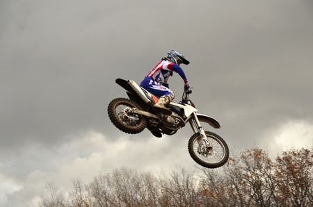 RUSSIA, SAMARA, CHAPAYEVSK - OCTOBER 17: Extreme jump moto racer A.Nikishkin on the background of clouds the Open Cup "Volga" motocross on October 17, 2011 in Chapayevsk, Samara, Russiaのeditorial素材