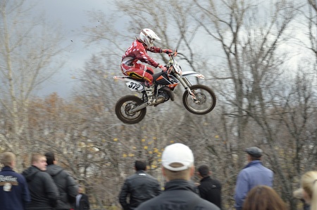 RUSSIA, SAMARA, CHAPAYEVSK - OCTOBER 17: Flying over the audience rider I.Baranov on the background an autumn forest the Open Cup "Volga" motocross on October 17, 2011 in Chapayevsk, Samara, Russiaのeditorial素材