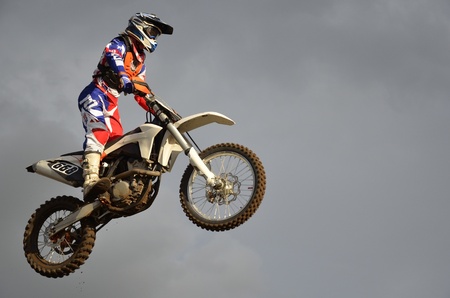 The spectacular jump motocross racer on a motorcycle on the background a stormy skyのeditorial素材