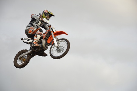 The spectacular jump motocross racer on a motorcycle on the background a stormy skyのeditorial素材