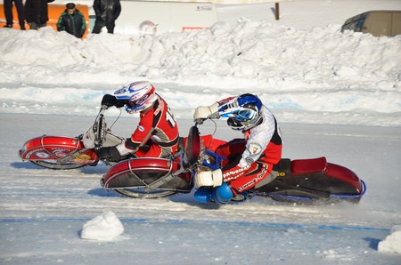 SAMARA, RUSSIA - JANUARY 27: Racing on ice, two unknown driver on a motorcycle with spikes rotates with a large slope on one knee on the ice speedway practice Championship January 27, 2012 in Samara, Russiaのeditorial素材