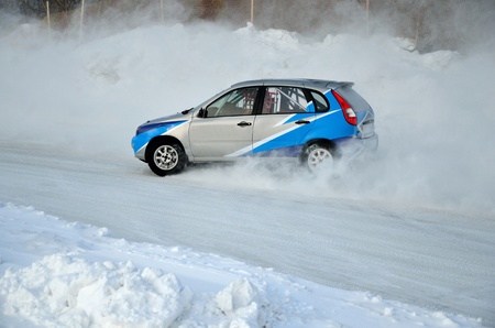 Sports car by turning the glides on the track in the thick dust of snow, in winter track motor racingの写真素材