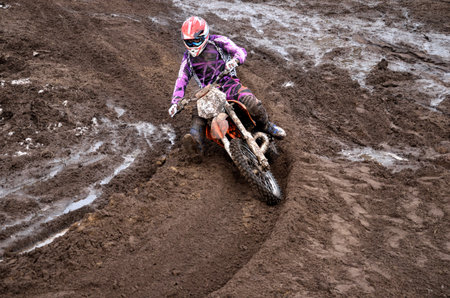 The driver put the right foot forward at the beginning of a deep rut turning sandy motocross track