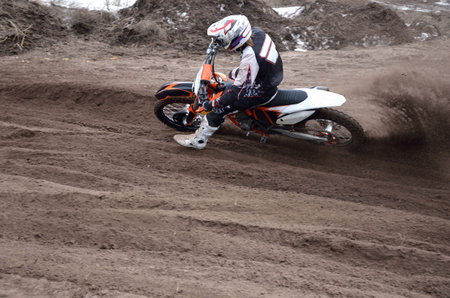Motocross rider veering point-blank of sand with a large plume out from under the rear wheel